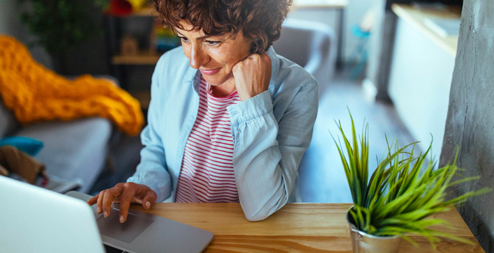 Une femme souriante utilisant son ordinateur, détendue